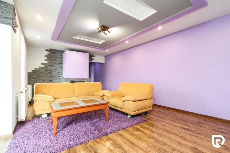 Living room with purple walls and a brown sofa in a family house.