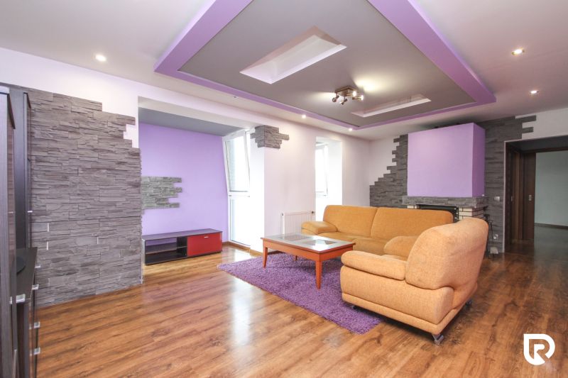 Living room with purple ceilings, a sofa, and a wooden decor floor in a family house.