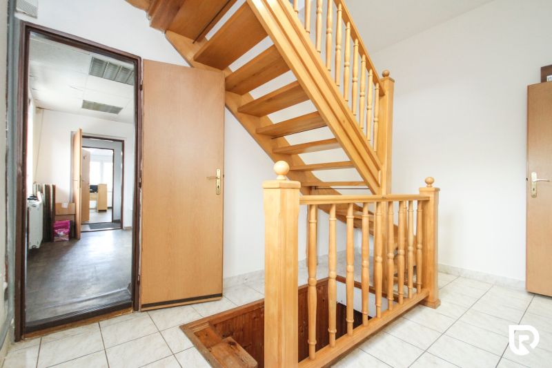Wooden staircase and tiles in the interior of a family house with rooms in the background.