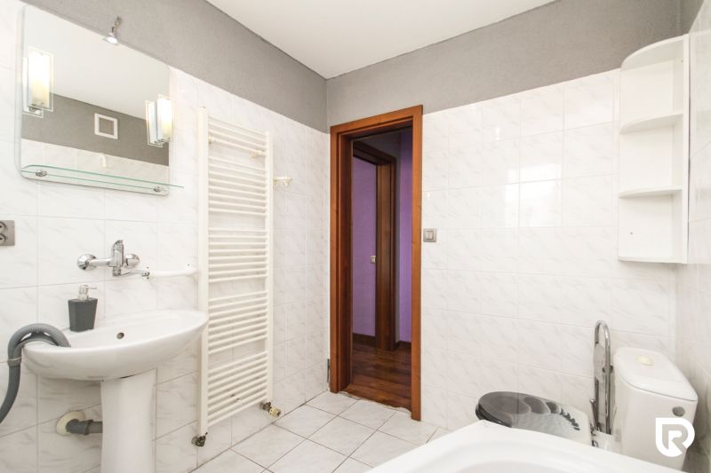 A bathroom in a family house with a sink, a bathtub, and white tiles.