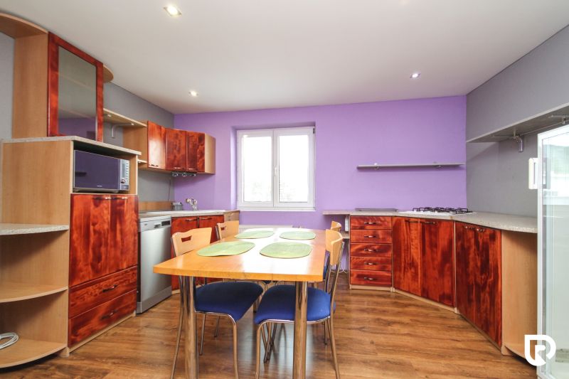 A kitchen in a family house with dark wood furniture and a floor with a wooden decor.