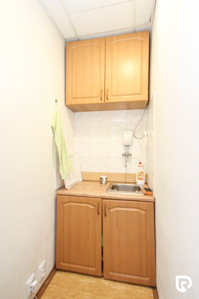A small kitchen with wooden cabinets and a sink in a family house.