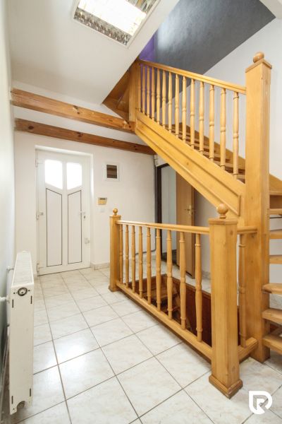 A staircase with a wooden railing and white tiles in a family house.