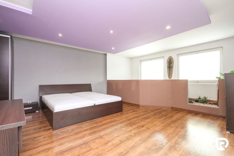 A bedroom in a family house with a wooden decor floor and a purple ceiling.