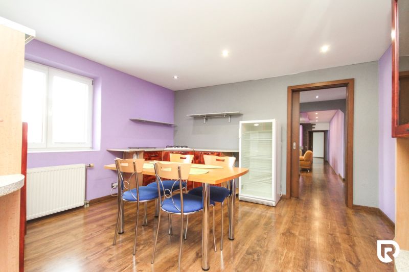 Dining area with chairs and a refrigerator in a family house, floor with wooden decor.