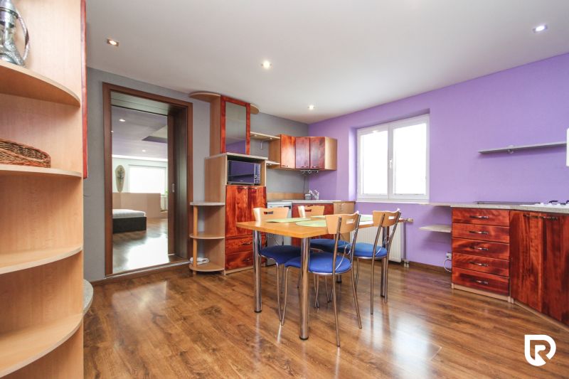 A kitchen in a family house with a wooden decor floor, wooden furniture, and a purple wall.