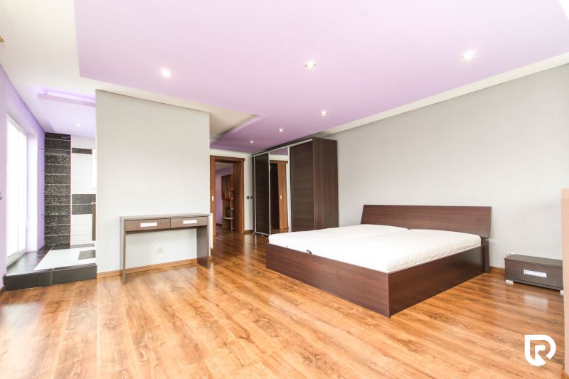 Bedroom with a bed, built-in wardrobe, and wooden decor flooring in a family house.