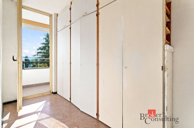 A built-in wardrobe next to the balcony in a 2-room apartment with a view of greenery.