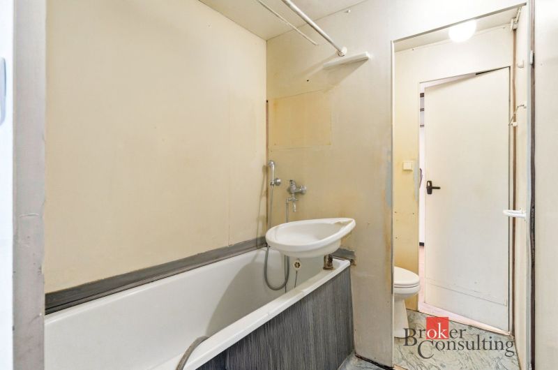 Bathroom in a 2-room apartment with a bathtub and a sink near the entrance door.