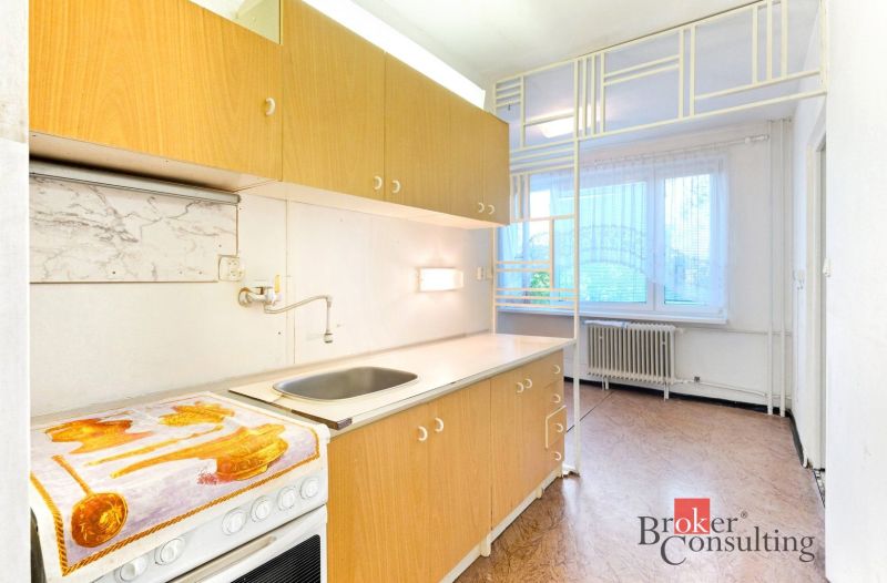 A kitchen with a unit in a 2-room apartment, a floor with a wooden decor, light walls.