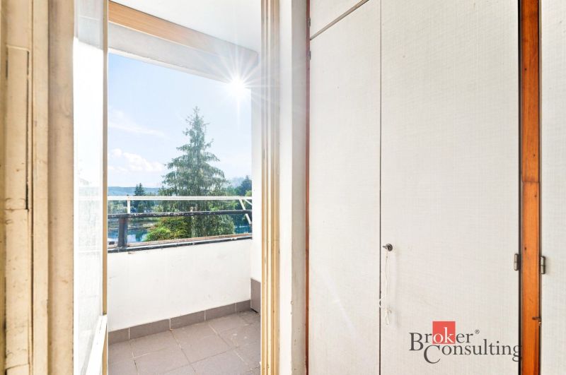 A balcony in a 2-room apartment with a view of greenery and a sunny horizon.