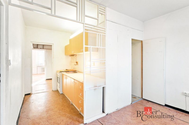 A kitchen in a 2-room apartment with a wooden decor floor and white walls.