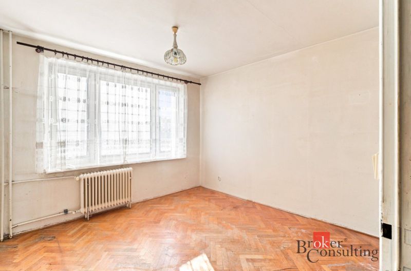 A room in a 2-room apartment with a wood-patterned floor and a large window.