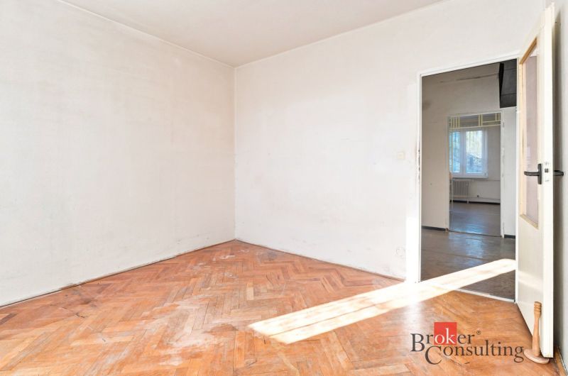 An empty room with white walls and a floor with a wooden decor in a 2-room apartment.