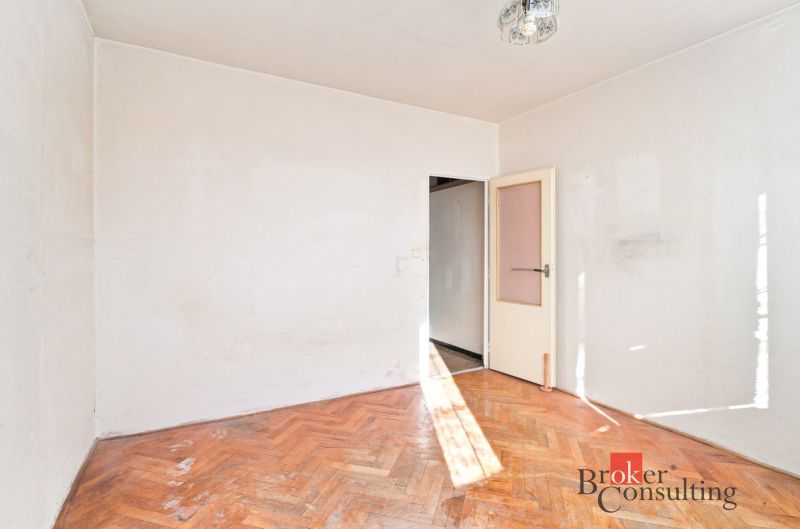An empty room with wood-patterned flooring in a two-room apartment, neutral interior.