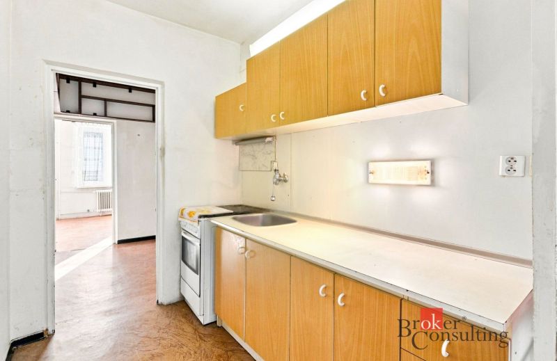 A kitchen in a 2-room apartment with a wooden decor floor and a simple kitchen unit.
