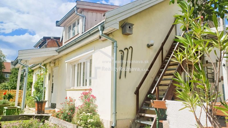 A family house in Rožňava with an outdoor staircase and a flower garden.