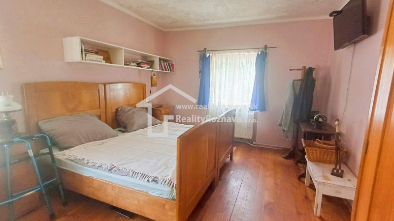 A bedroom in a family house with simple furniture, a bed, and shelves, a floor with a wooden decor.