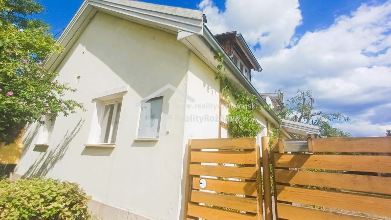 A family house in Rožňava with a fence and greenery, clear sky in the background.