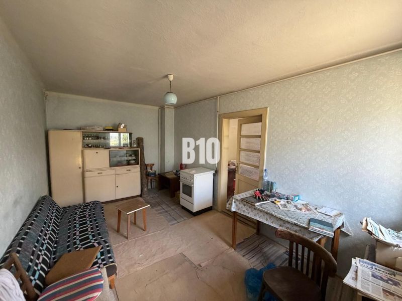 A room in a cottage with older furnishings; a sofa, a table, and a cupboard.