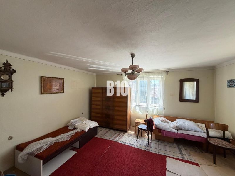 Room in a cottage with a bed, wardrobe, and retro decorations.