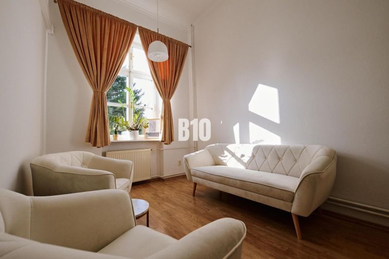A bright office with comfortable cream sofas and a wooden decor floor.