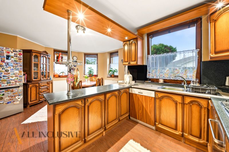 Traditional kitchen in a family house with wooden cabinets and a large window.