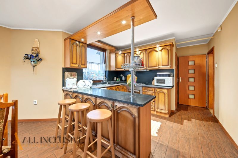 A kitchen in a family house with a bar counter and a wooden decor floor.
