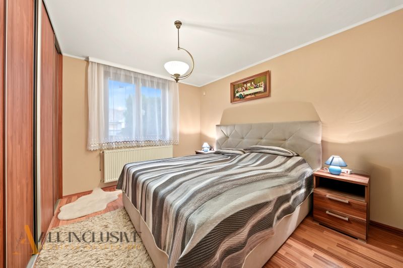 A bedroom in a family house with a wooden decor floor and a comfortable bed.