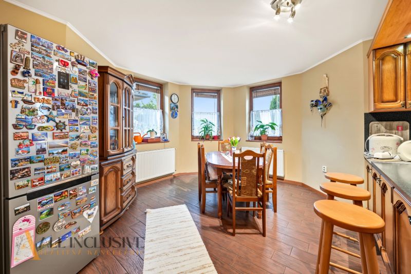 A kitchen in a family house with a refrigerator, wooden furniture, and a floor with a wooden decor.