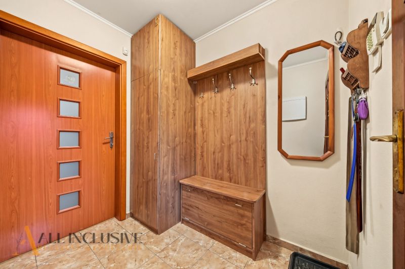Entrance hall in a family house with wooden decor, mirror, and tiles.