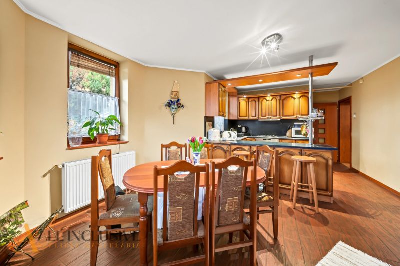 Dining area and kitchen in a family house with a wooden decor floor.