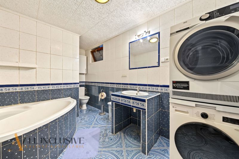 A bathroom with a shower, double sink, and washing machine in a family house.