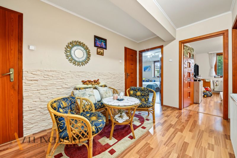 Living area with rattan furniture, wooden decor flooring, family house.