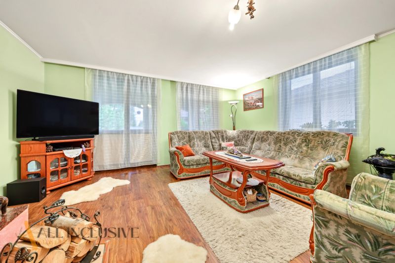 Living room in a family house with a sofa, television, and wooden decor flooring.