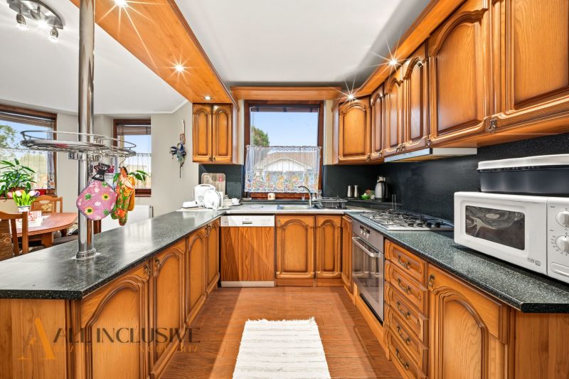 A kitchen with wooden cabinets and a wood-patterned floor in a family house.
