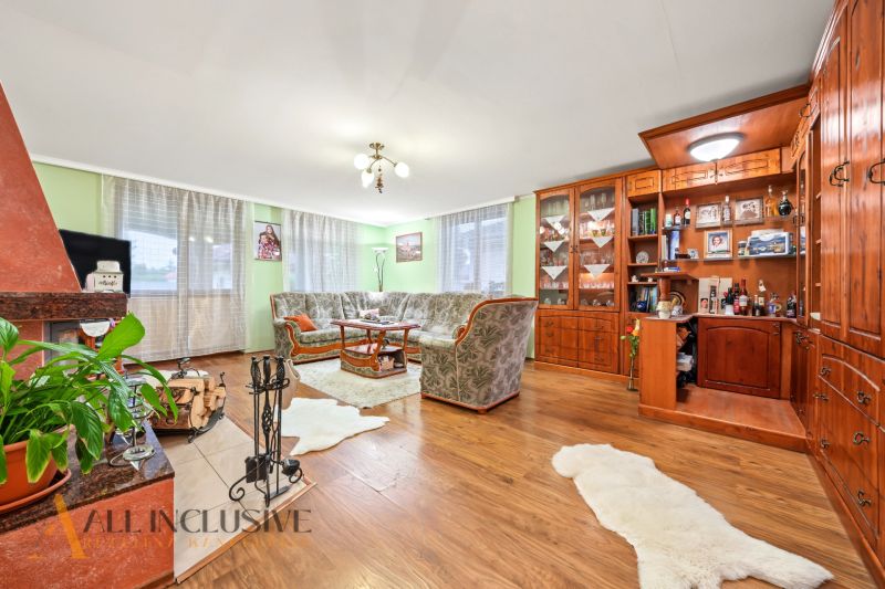 Living room of a family house with a fireplace, sofa, and wooden decor flooring.