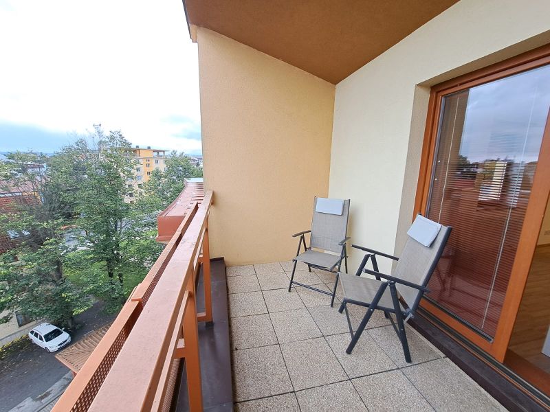 A balcony in a 2-room apartment on Štefánikova Street in Poprad with two chairs.