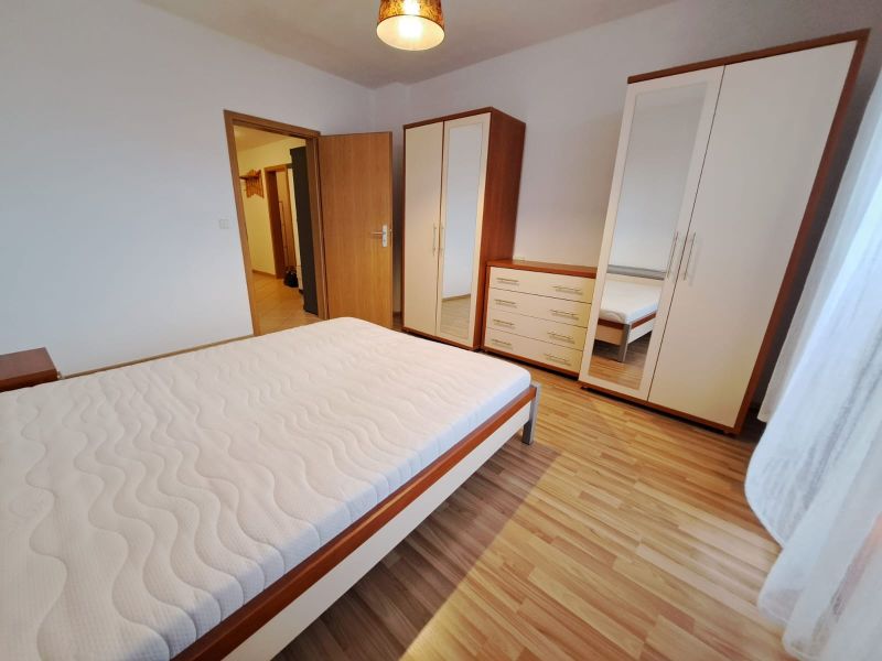 Bedroom in a two-room apartment with wood-patterned flooring and furniture.
