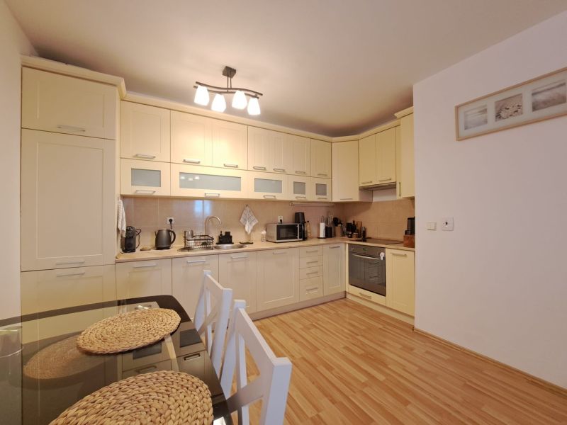A kitchen in a 2-room apartment with a wooden decor floor and a dining table.