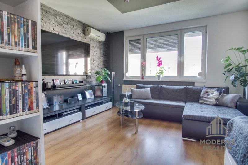Living room in a 3-room apartment with a corner sofa and a floor with a wooden decor.