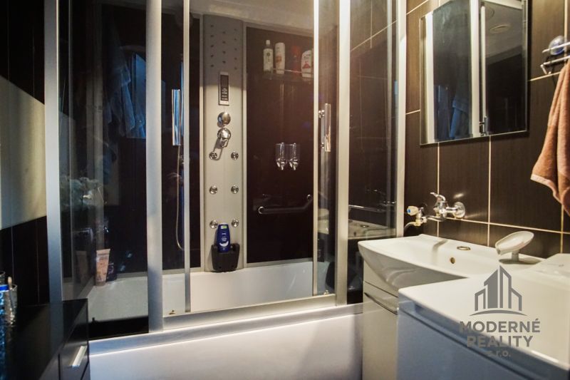 A bathroom in a 3-room apartment with dark tiles and a shower corner.