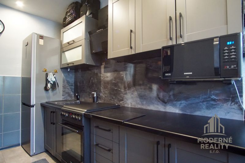 A kitchen in a 3-room apartment with gray cabinets and modern appliances.