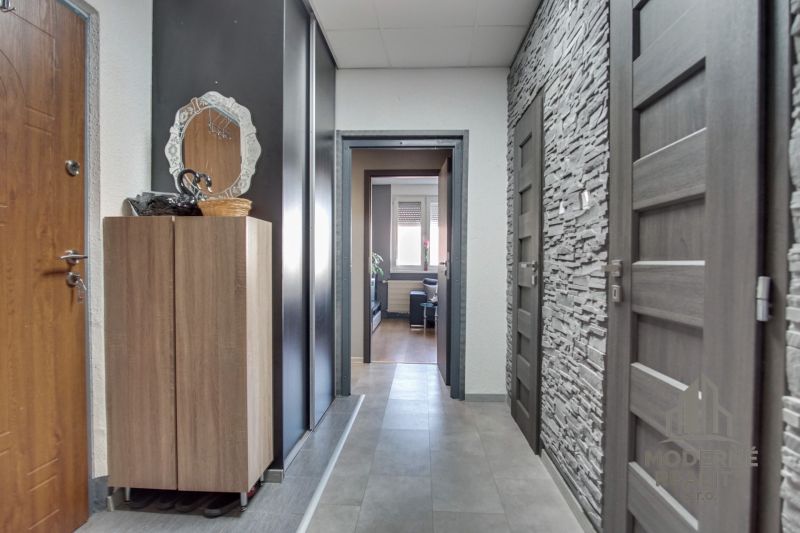 A hallway in a 3-room apartment with a wardrobe, a mirror, and stone cladding on the wall.