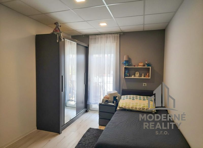A bedroom in a three-room apartment with dark furniture, a shelf, and a floor with a wooden decor.