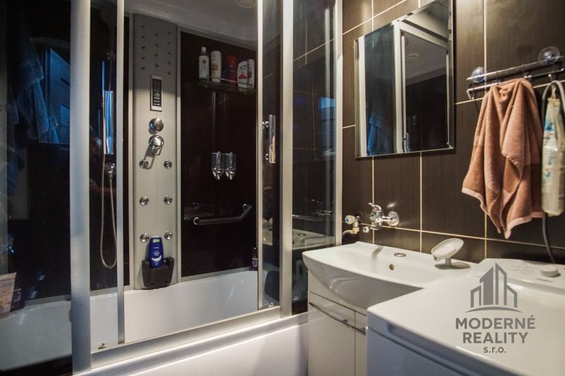 A bathroom in a 3-room apartment with a large shower and dark tiles.
