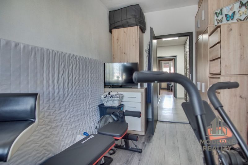 A room with a wooden decor floor and fitness equipment in a 3-room apartment.