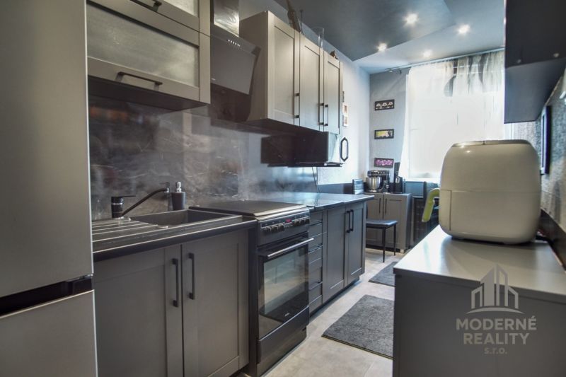 A kitchen in a 3-room apartment with gray cabinets and stainless steel appliances.