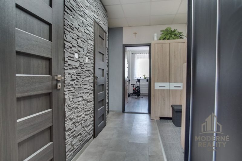 Entrance hall of a 3-room apartment with a stone wall imitation and gray doors.