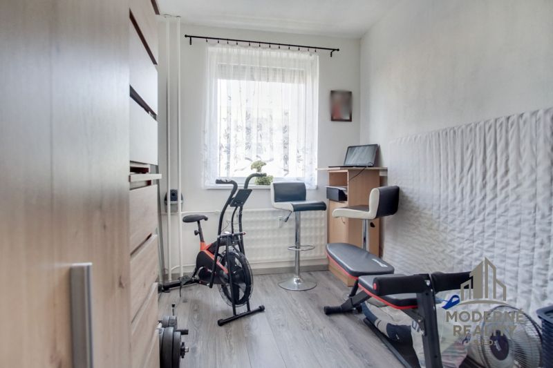 Home gym with an exercise bike and a bench, floor with wood decor.